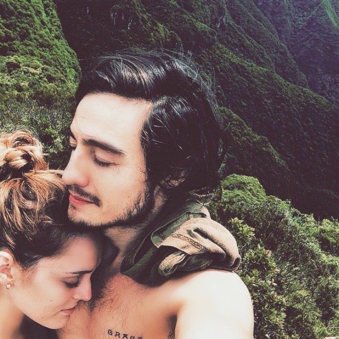 pareja en paisaje de montañas abrazados con ojos cerrados 