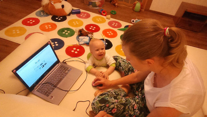 madre en lap top y bebe en el suelo llorando