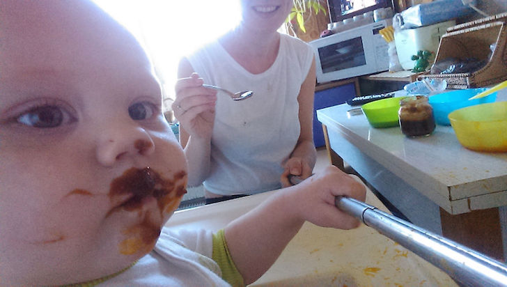 bebe manchado de comida y madre en la cocina