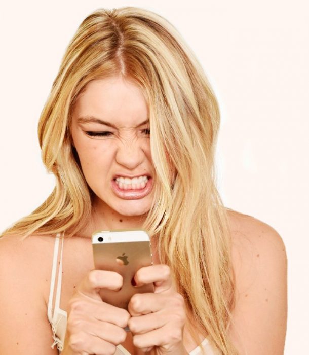 mujer rubia con celular en la mano enojada 