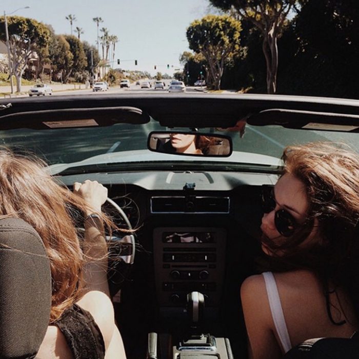 dos mujeres manejan en la ciudad con convertible 