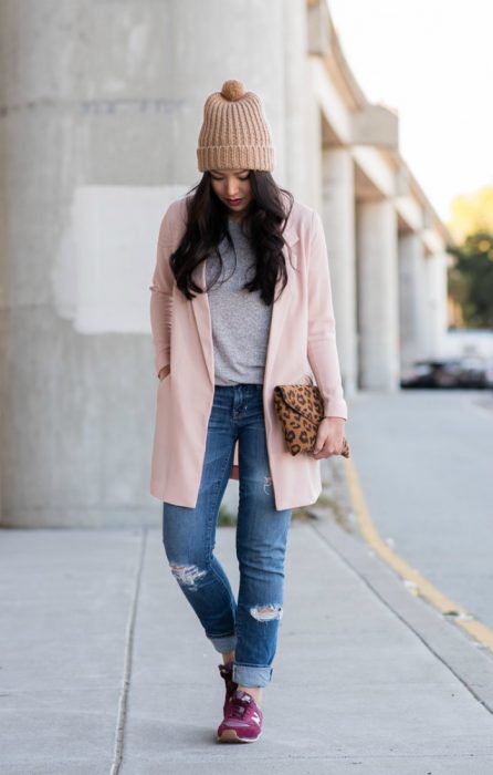 mujer caminando en la calle con gorro y saco rosa pastel 