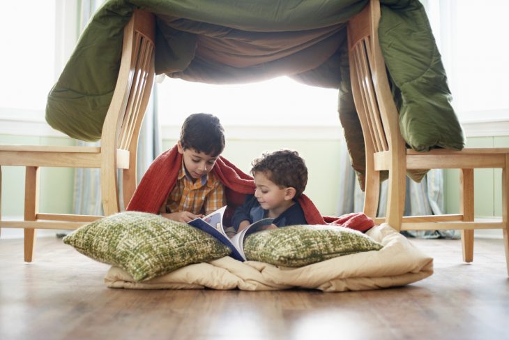 niños en el suelo leyendo con almohadas 