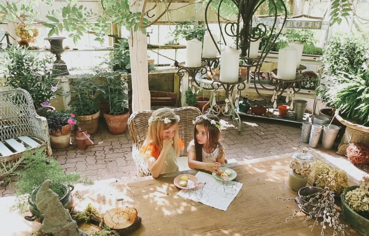 dos niñas sentadas en la mesa con plantas 