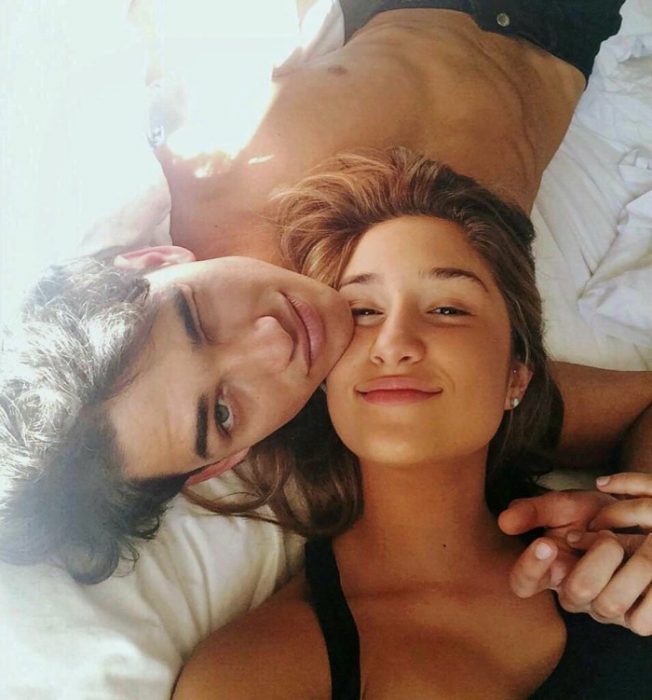 Chica y hombre en la cama sonrién