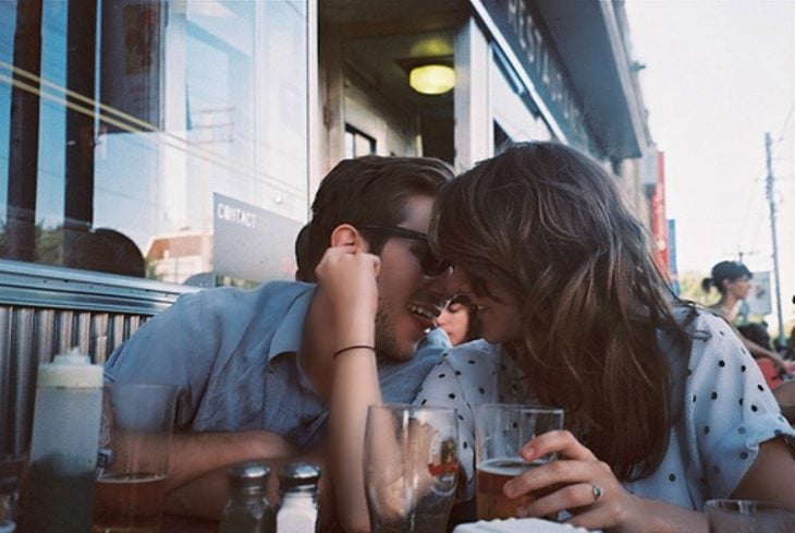 hombre y mujer sentados en una mesa a punto de besarse