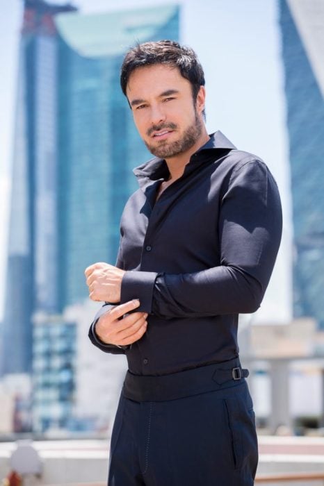 Alejandro lópez, actor, posando para una revista con camisa negra y pantalón a juego