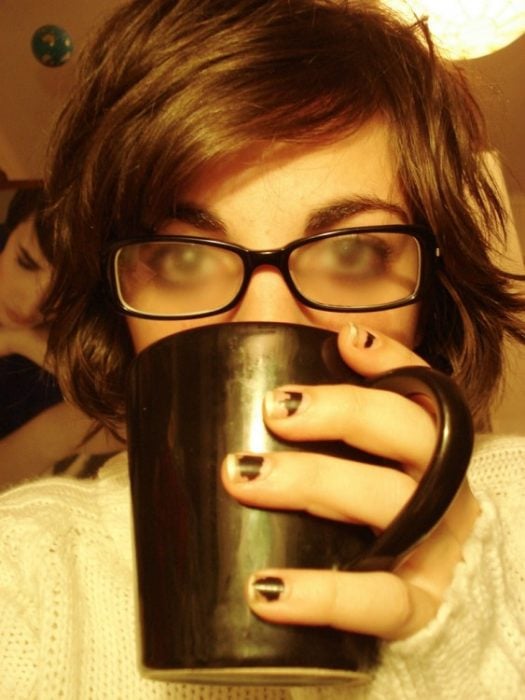 chica tomando bebida caliente con lentes empañados