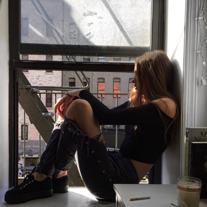 Chica sentada en la ventana viendo hacia la calle 
