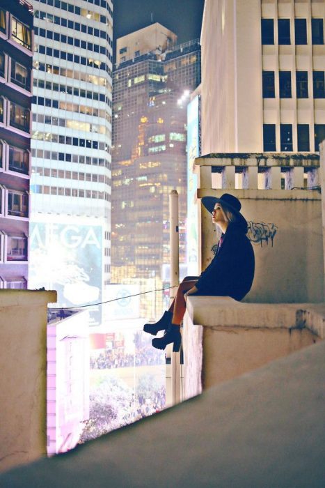 Chica sentada en una azotea viendo hacia el cielo 