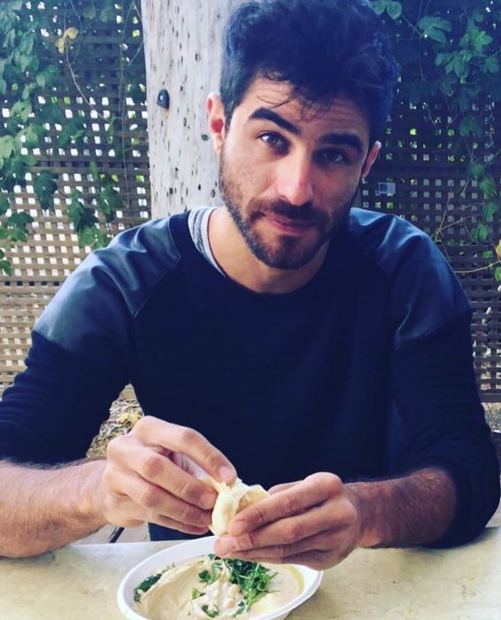 hombre con camisa azul comiendo con las manos 