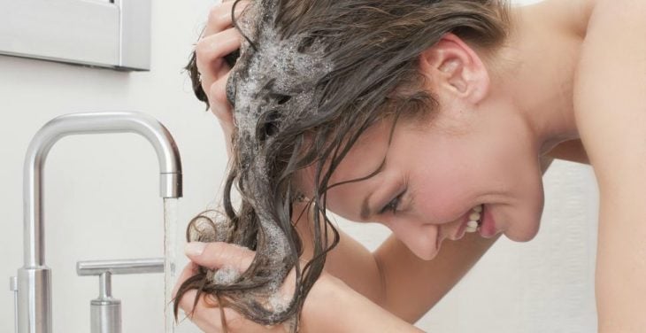 mujer mojandose el cabello en llave del agua 