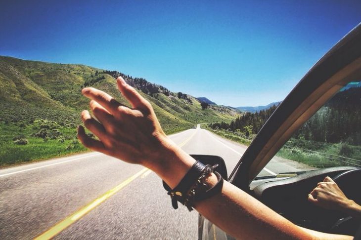 mano de chica por ventana de coche en carretera