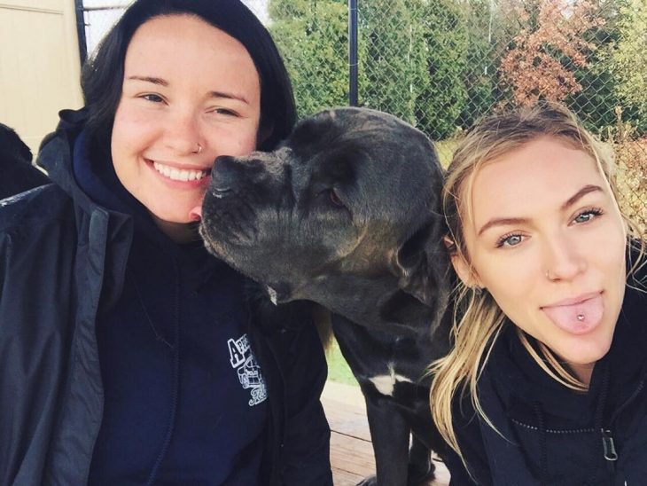 dos amigas con un perro negro en medio 