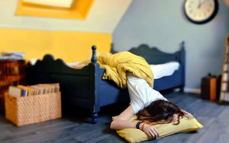 Chica durmiendo con medio cuerpo fuera de la cama