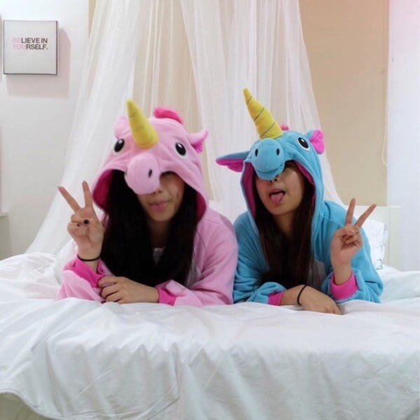 Chicas recostadas sobre una cama vestidas como unicornios 