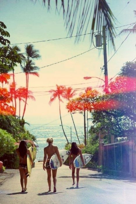 chicas con tabla de surf caminando