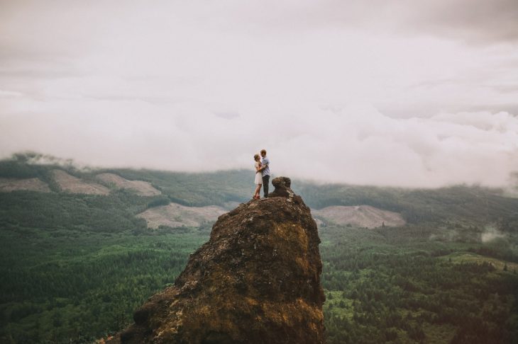 pareja de pie en una montaña con paisaje alrededor 