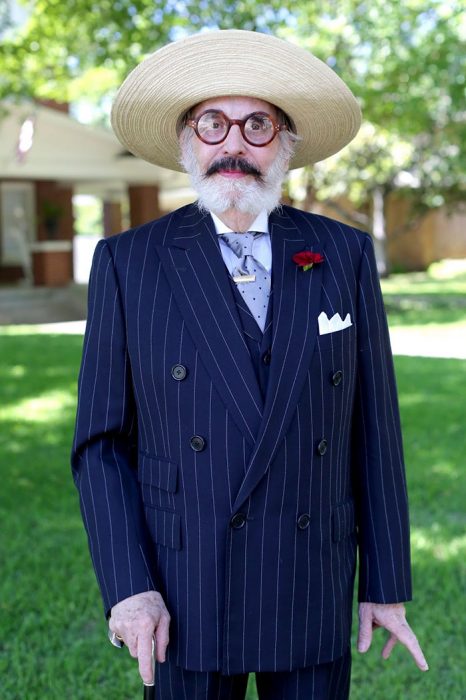 Hombre mayor usando un traje en color azul con rayas blancas y un sombrero de paja 