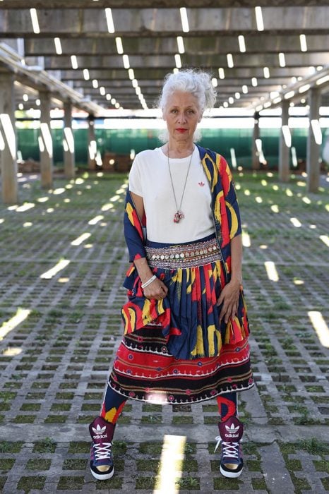 Mujer mayor usando un conjunto de falta y saco con estampado tribal y tenis nike