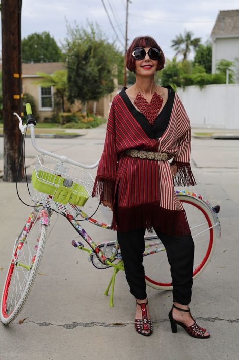 Mujer mayor usando un conjunto rojo parada frente a una bicicleta 