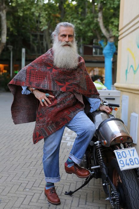 Hombre mayor con barba usando un poncho color rojo 