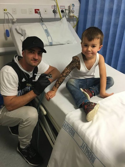 Artista del tatuaje creando tatuajes temporales para niño en un hospital 