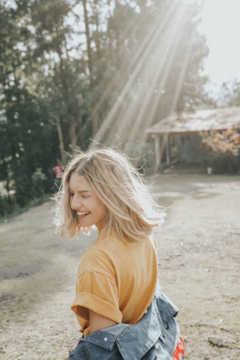 Personalidad de chica sagitario; mujer rubia de cabello corto riendo en la naturaleza 