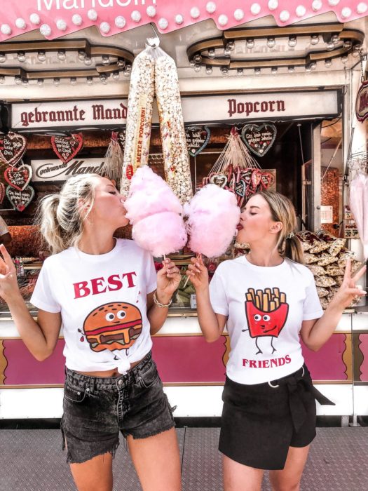 Personalidad de chica sagitario; mejores amigas en parque de diversiones comiendo algodón de azúcar rosa