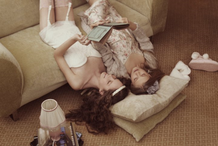 Chicas recostadas sobre el suelo leyendo un libro 
