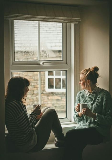 Chicas sentadas tomando café mientras miran por la ventana 