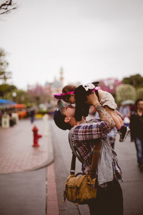 Padre besando a su hija mientras pasean por Disney 