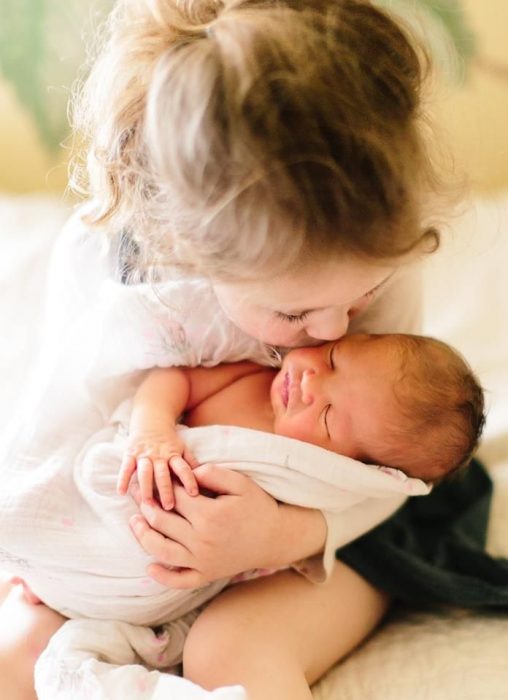 niña pequeña con bebé en brazos