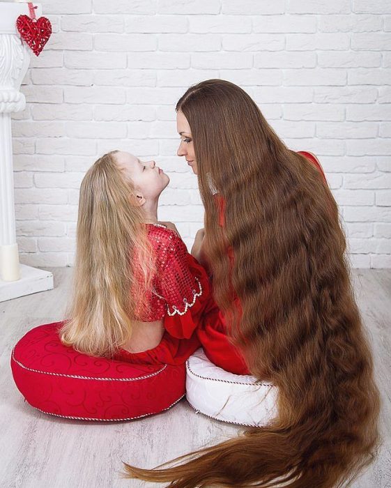 Madre e hija con el cabello largo hasta los tobillos mirándose de frente