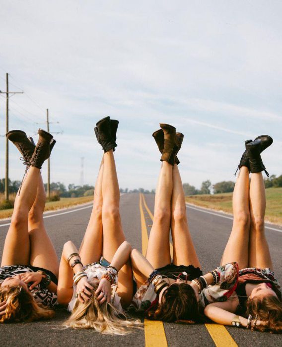 Chicas recostadas en la carretera con los pies arriba 