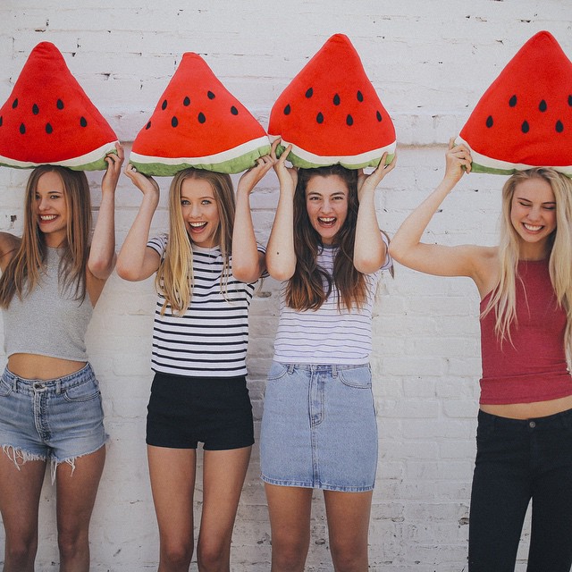 Chicas sosteniendo rebanadas de sandia sobre sus cabezas 