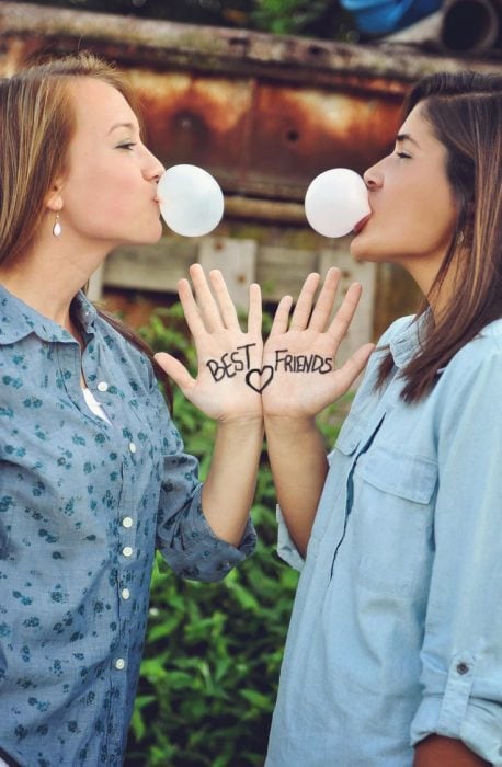 Chicas mascando chicle y mostrando sus manos con la frase best friends 
