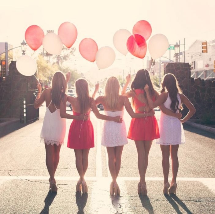 Chicas sosteniendo globos mientras caminan por la carretera 