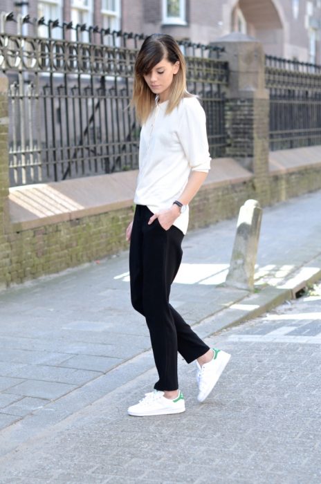 Chia usando una blusa blanca, pantalón negro y zapatillas blancas 