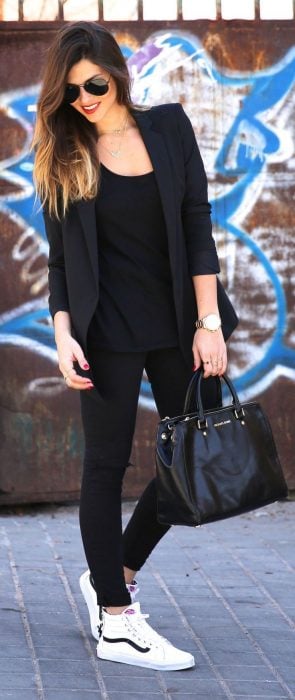 Chica usando un traje en color negro y zapatillas de color blanco 
