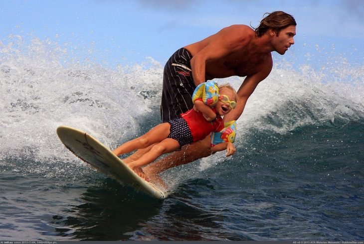 NIÑA SURFEANDO EN LAS PIERNAS DE SU PADRE