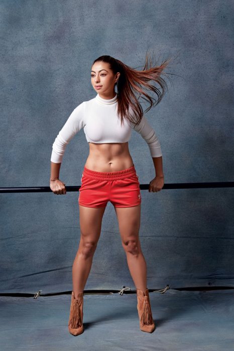 Mujer musculosa posando para la revista Elle en blusa blanca y shorts rojos 