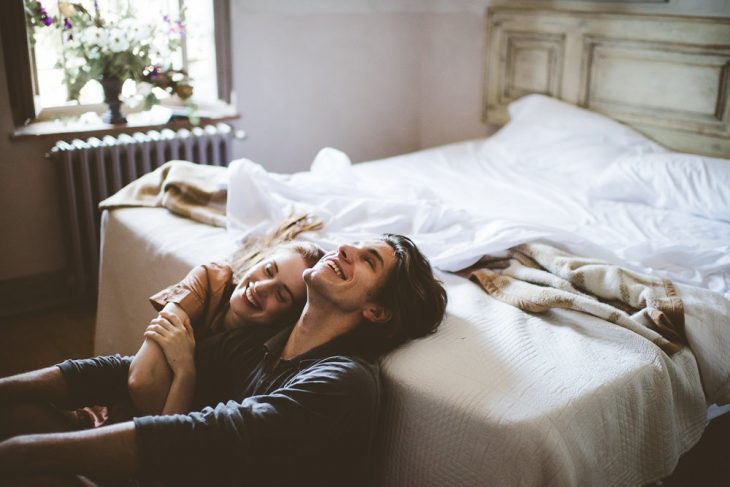 Pareja riendo recostados en una cama 