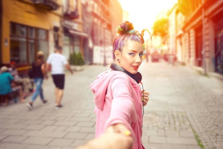 Chica caminando de la mano de su novio mientras ven una puesta de sol 