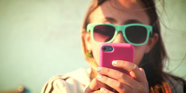 chica con celular en la playa