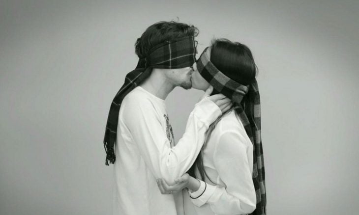 pareja con ojos vendados mientras se besan 