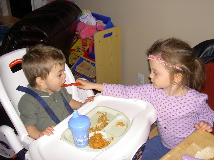 hermanita mayor dando de comer a hermano