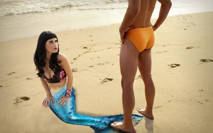 mujer cola de sirena sentada en la playa con hombre enfrente