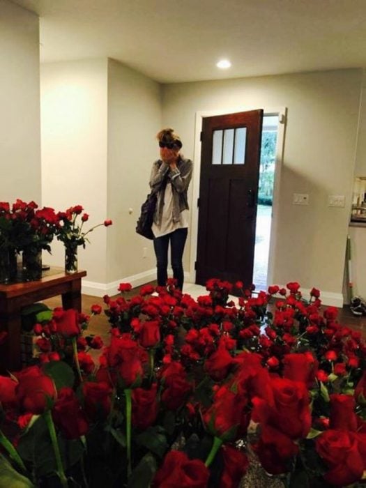 mujer sorprendida con rosas rojas en su casa 