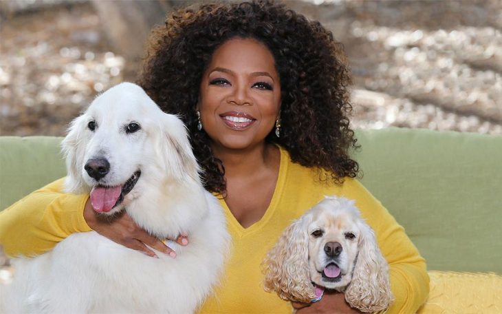 mujer morena sonriendo y abrazando a dos perros 